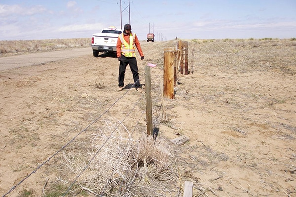 Surveyor by fence in field