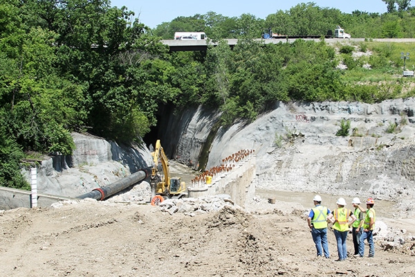 Team members stand above streambed to view bulkhead.