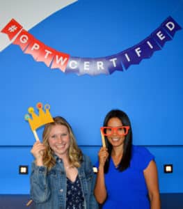 Two McClure employees pose under 'GPTW Certified' sign